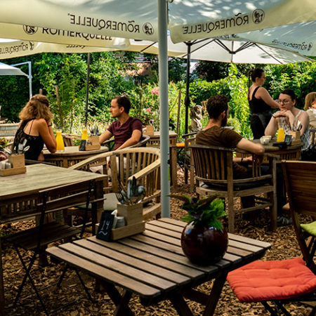 Schadzi outdoor garden terrace with wooden tables under umbrellas